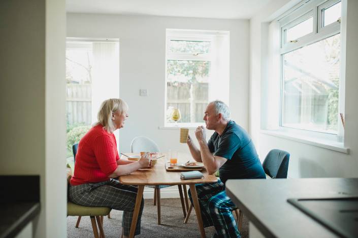 two house sitters sharing a hot drink over a breakfast table